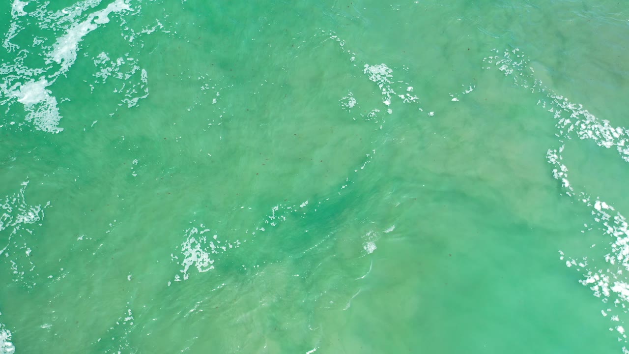 Turquoise sea texture with faint ripples and small white highlights.