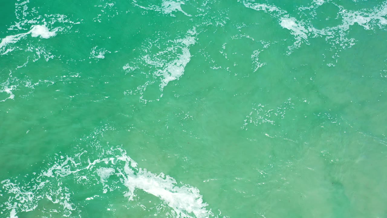 Green ocean surface with scattered white foam.