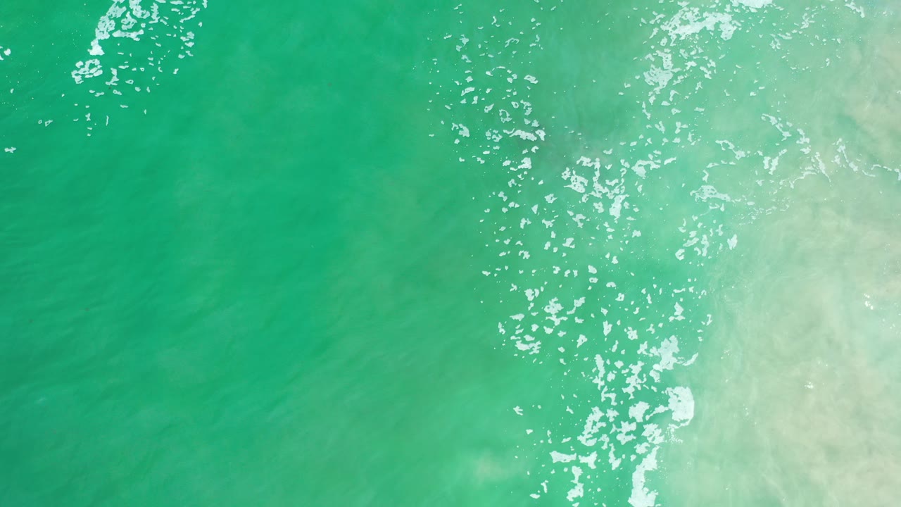 Turquoise ocean water with white foam and pale shallows