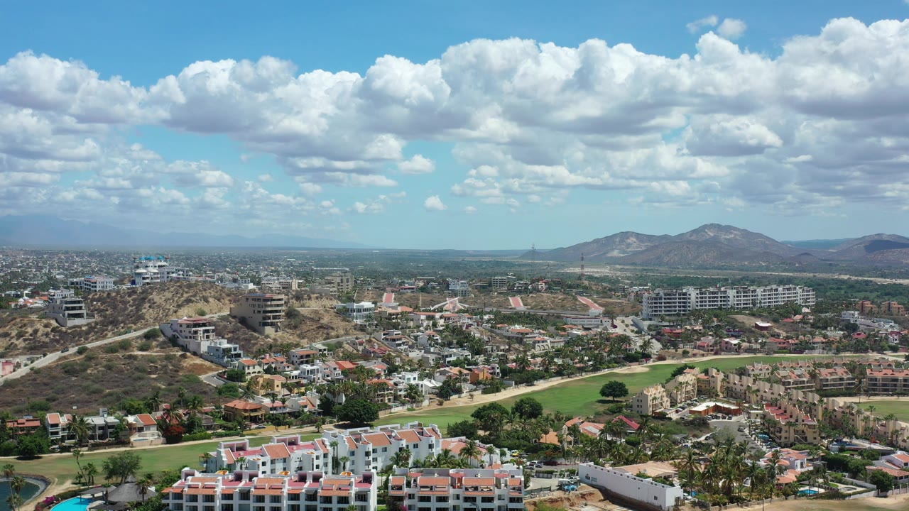 Elevated neighborhood view with mountains and scattered clouds in the distance.