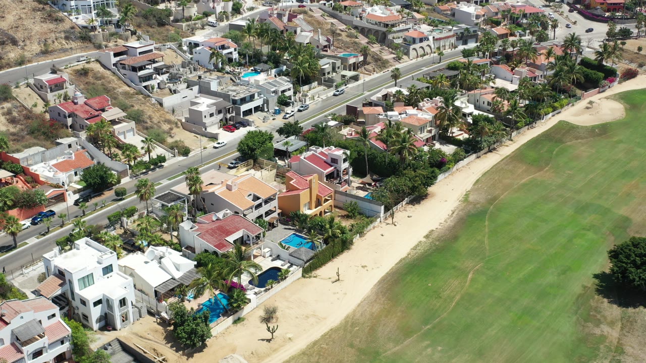 Aerial view of houses beside a green park and road.