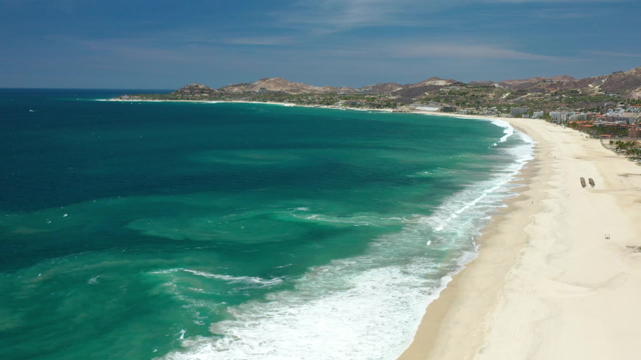 Aerial view of turquoise ocean meeting a wide sand beach.