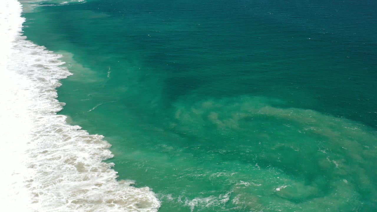 Teal ocean with white waves at left