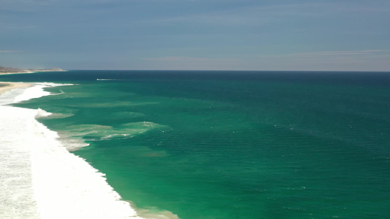 Ocean horizon above green water and foamy shore