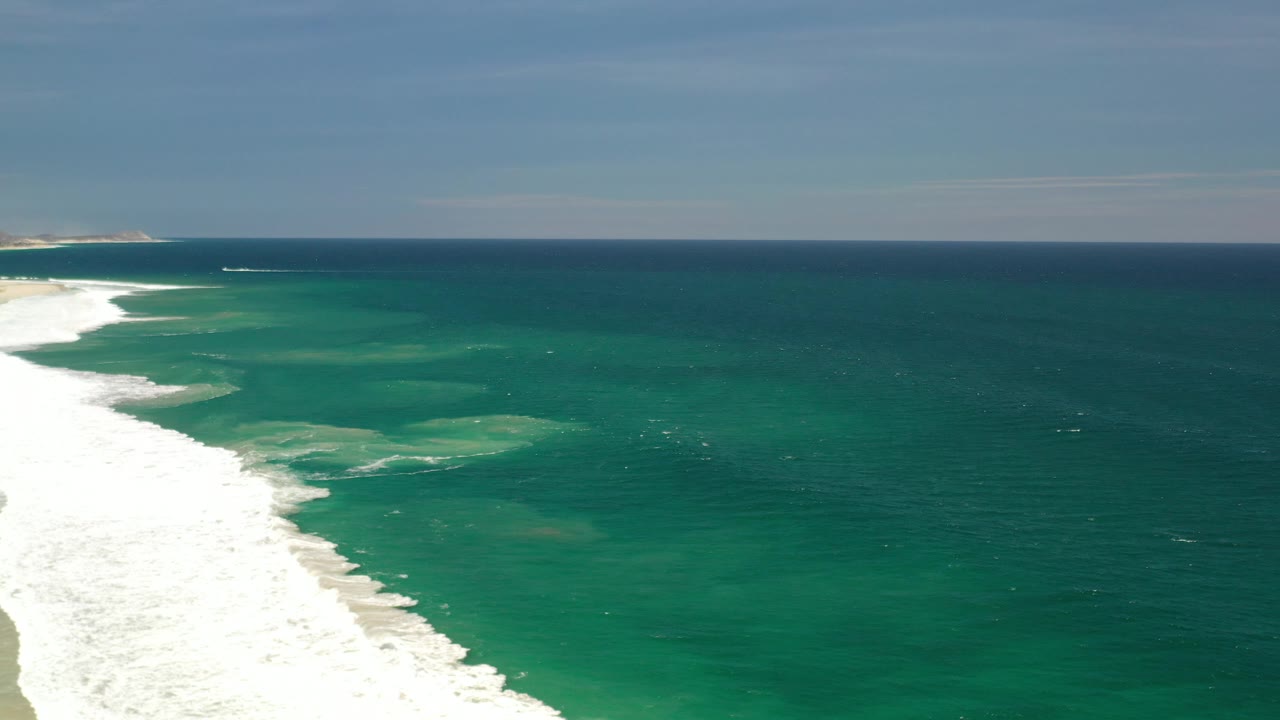 Green coastal water with white waves rolling onto shore