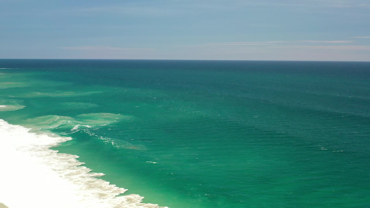 Wide elevated view of turquoise ocean off Los Cabos with white surf entering from the lower left and no visible people.