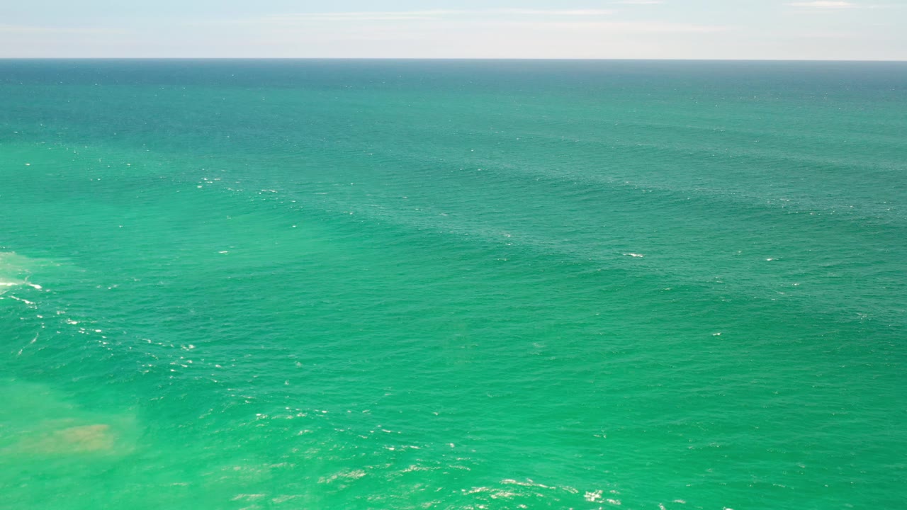 Wide view of turquoise water with a small line of white disturbance near midframe.