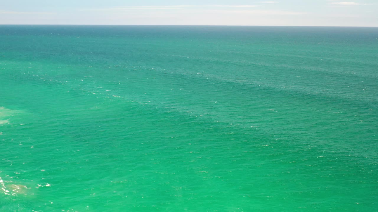 Los Cabos ocean surface fills the frame with teal water, scattered whitecaps, muted underwater color patches, and no visible people.