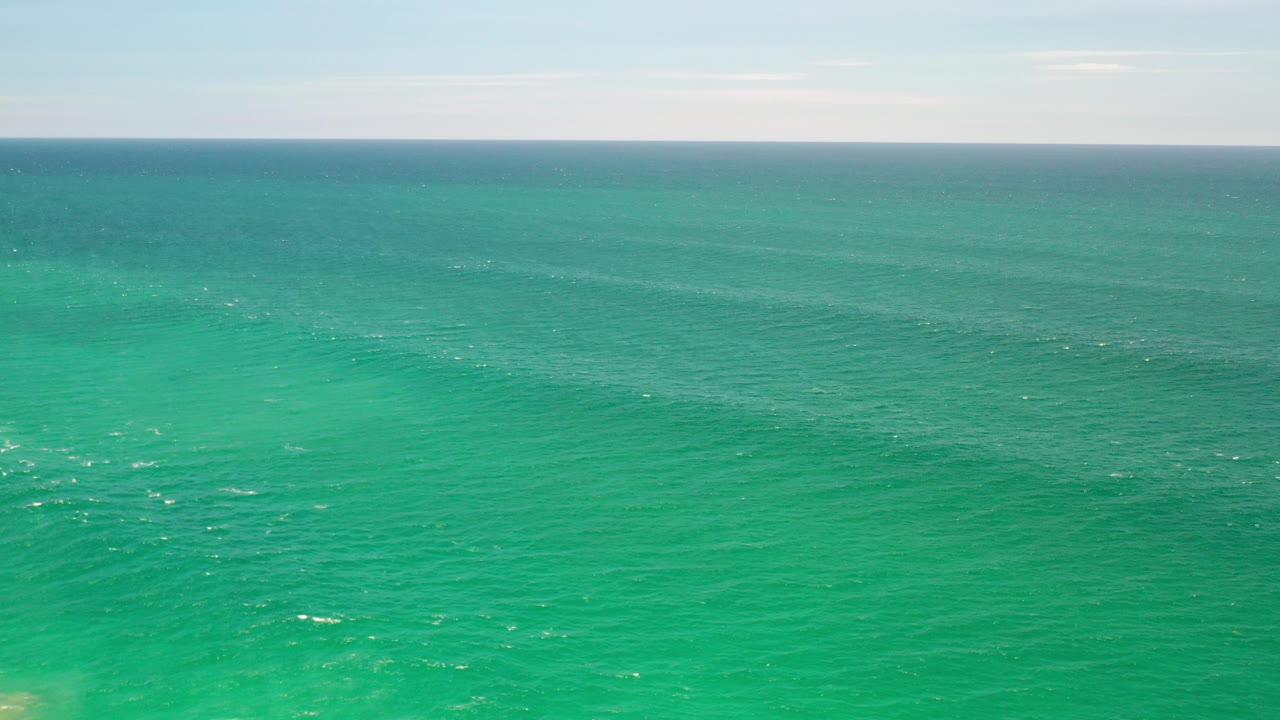 Wide green ocean with a distant horizon and pale sky.