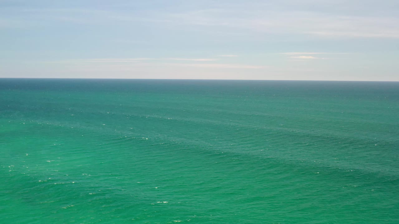 Los Cabos, Mexico ocean view with blue-green water filling the frame, small sunlit ripples, a distant horizon, and no visible people.