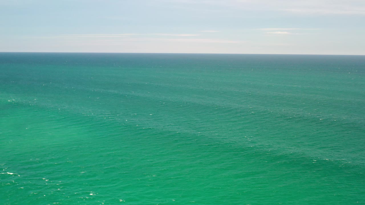 Opening frame of turquoise ocean off Los Cabos, Mexico, with a pale sky band at the horizon and no visible people.