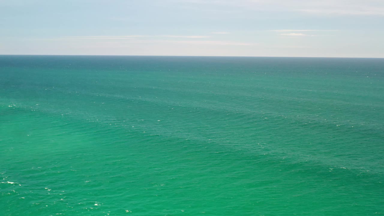 Aerial ocean frame from Los Cabos, Mexico, showing green-blue water, scattered surface glints, and no visible people.