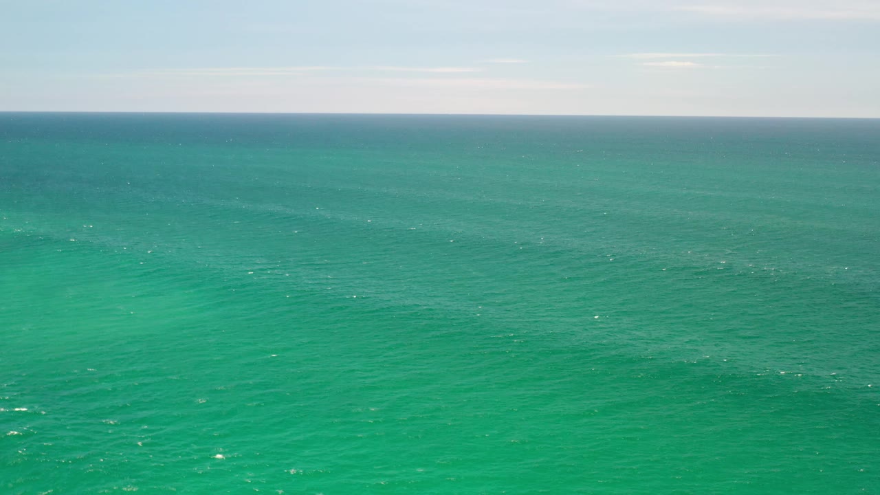 Wide ocean surface with turquoise water and soft sky above.