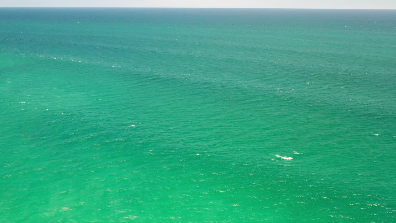 Opening view of the turquoise sea at Los Cabos, Mexico, with a pale sky band above the horizon and no visible people.
