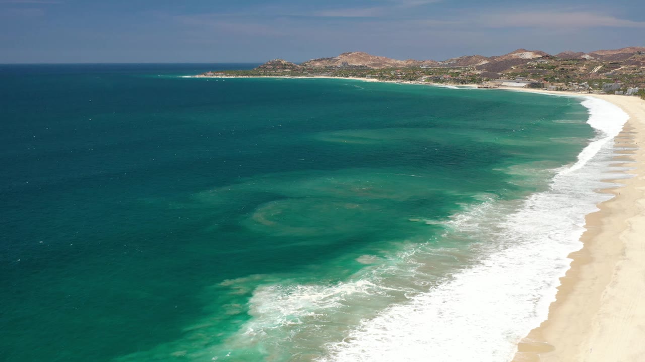 Curving surf line along a wide sandy Los Cabos beach