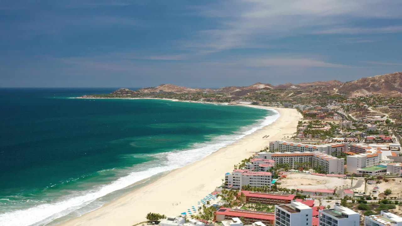 High coastal aerial with ocean, surf, beach, and town.