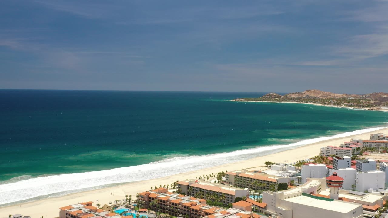 Ocean and beach with resort blocks and pools along the lower right.