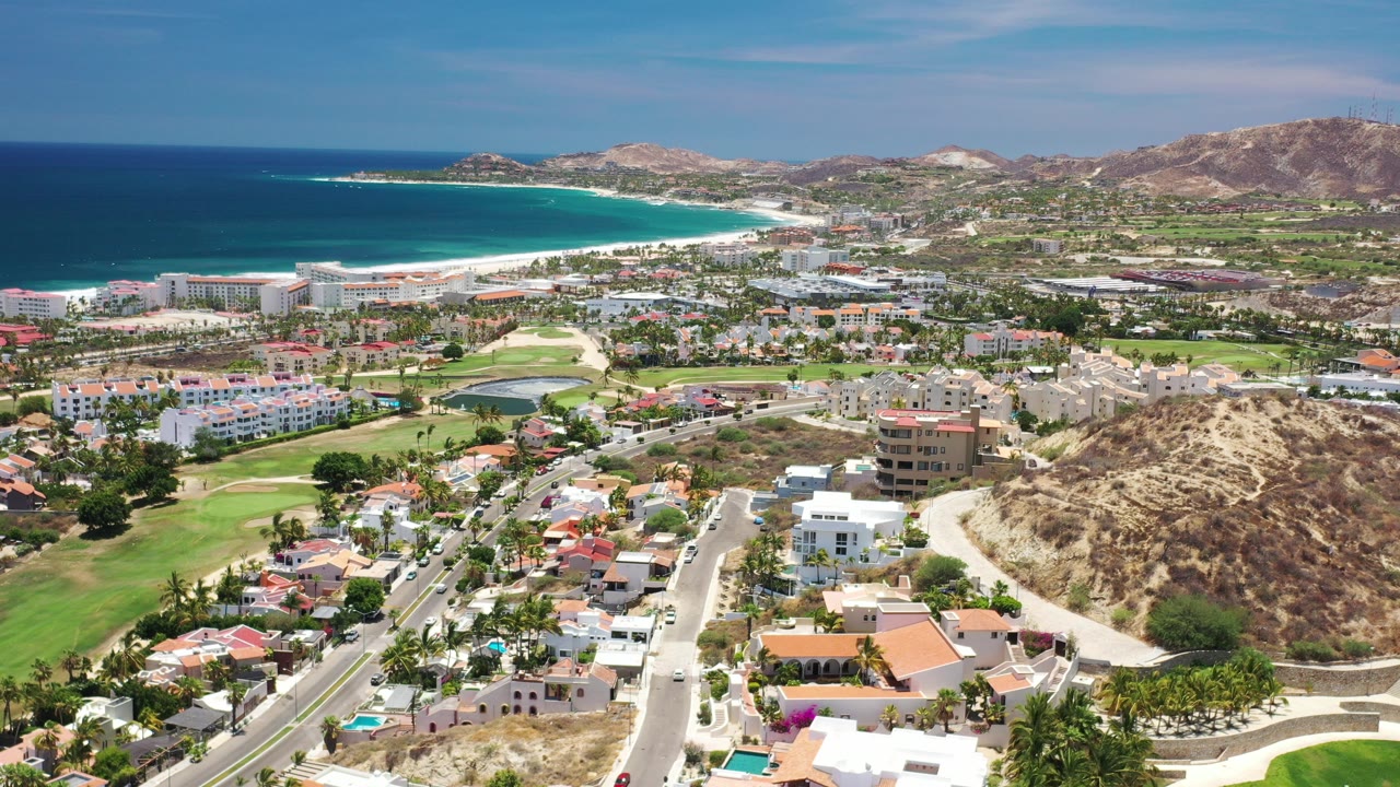 Aerial view of coastal town, beach, golf course, homes, and dry hills