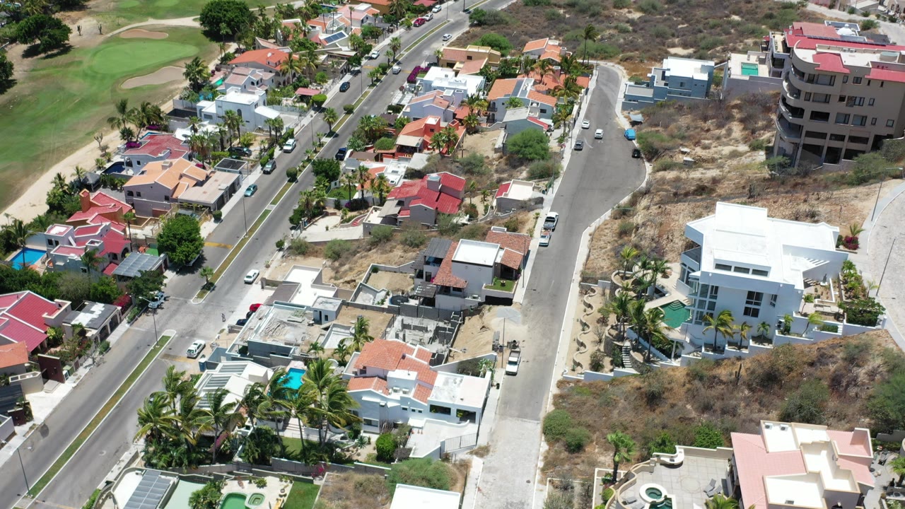 High aerial view of houses, streets, pools, and dry lots.