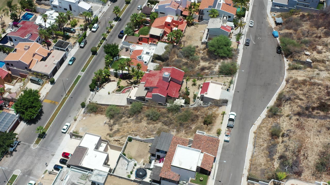 Aerial view of residential streets, houses, parked cars, and dry lots.