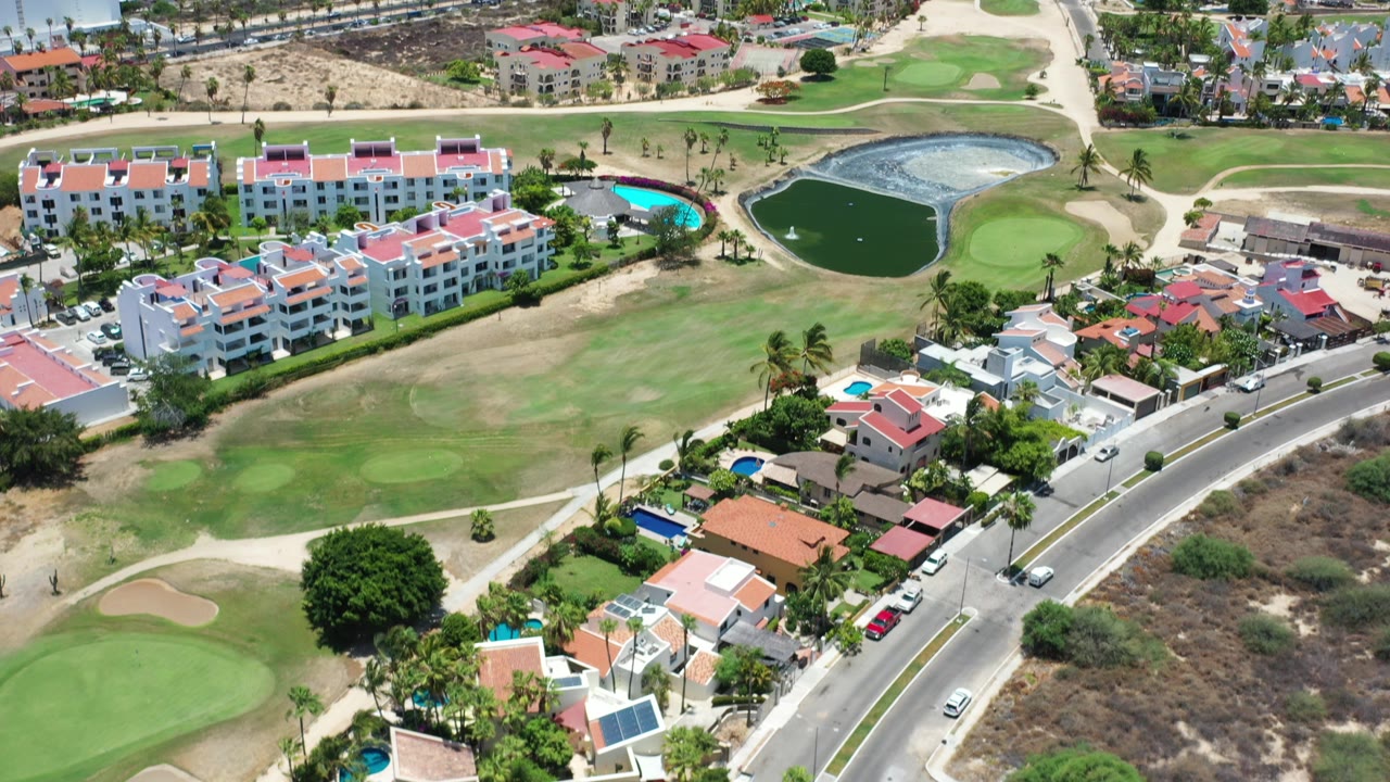 Aerial view of golf greens, homes, ponds, and oceanfront buildings.