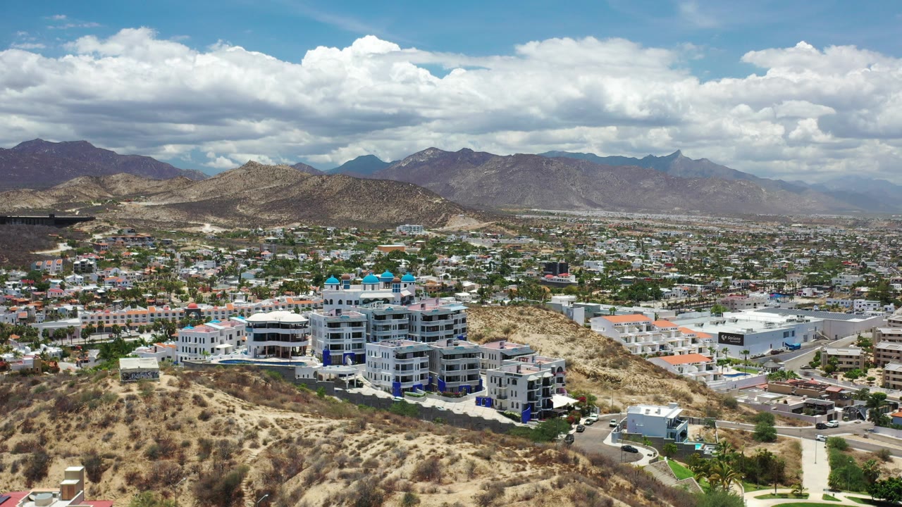 Aerial view over dry hillside buildings and a Los Cabos cityscape