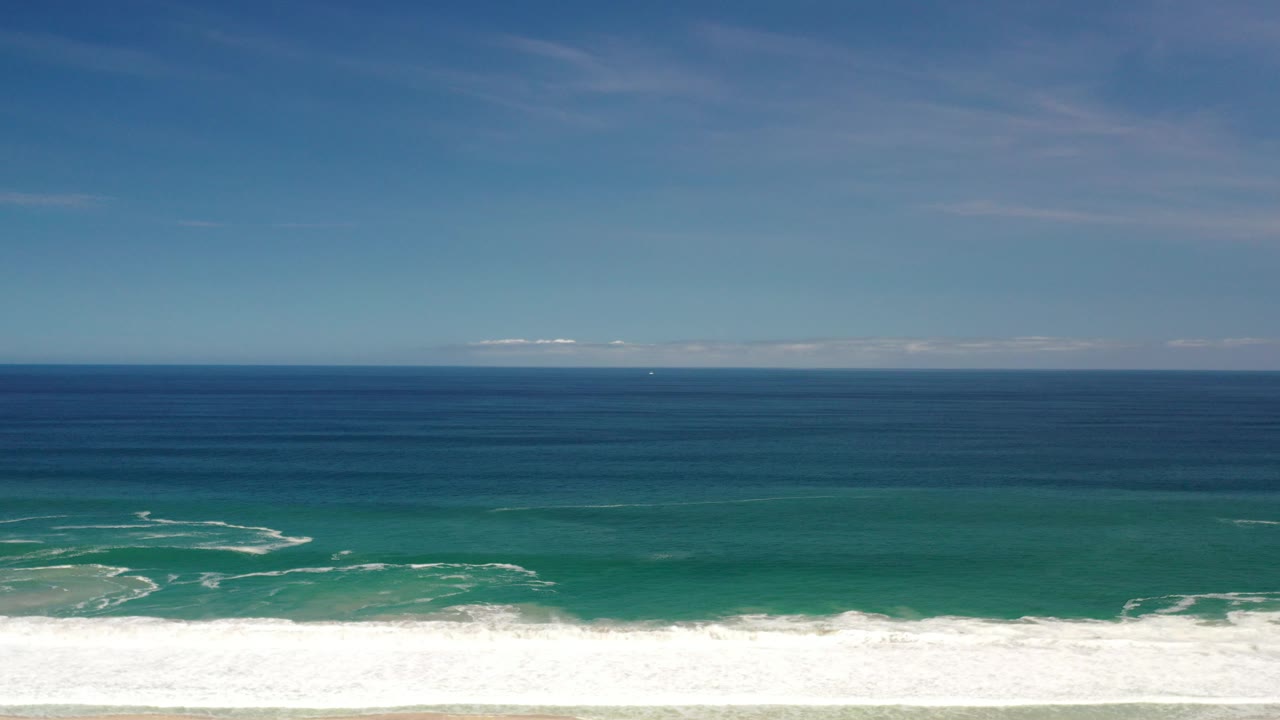 Ocean horizon with green shallows and curling white wave patterns.