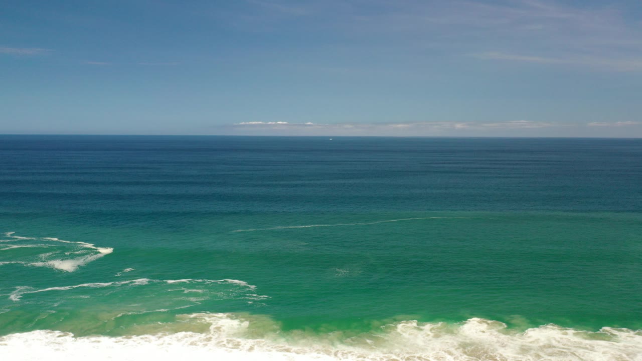 Aerial view of turquoise ocean and white surf under a blue sky