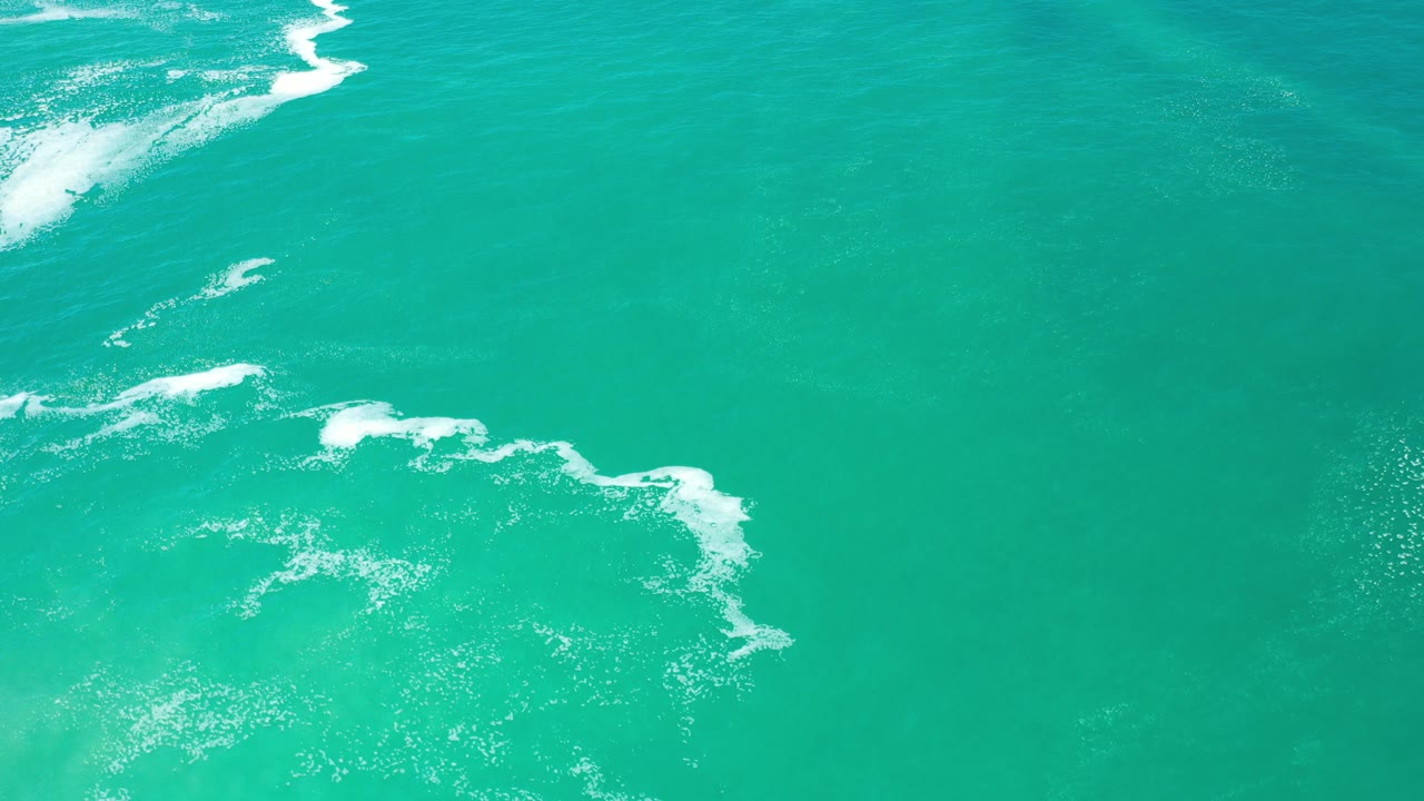 Turquoise ocean water with white sea foam seen from above.