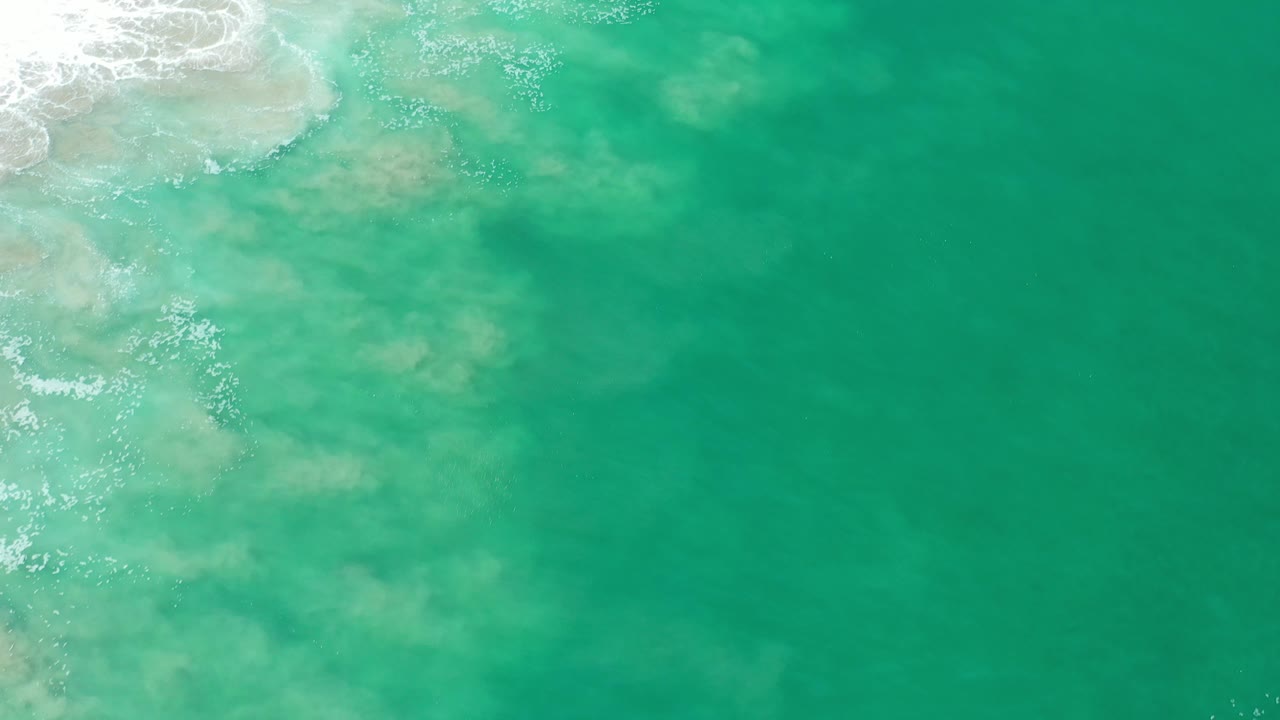 Overhead ocean surface with surf foam near the top left