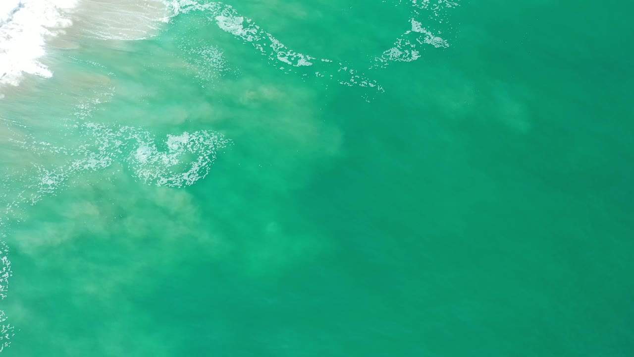 Translucent green water with surf foam at top left.