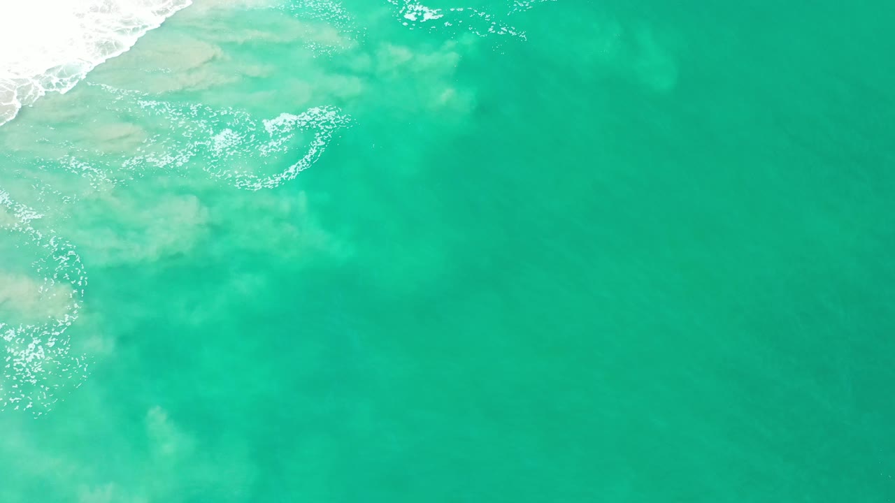 Open turquoise sea with surf and cloudy underwater color.