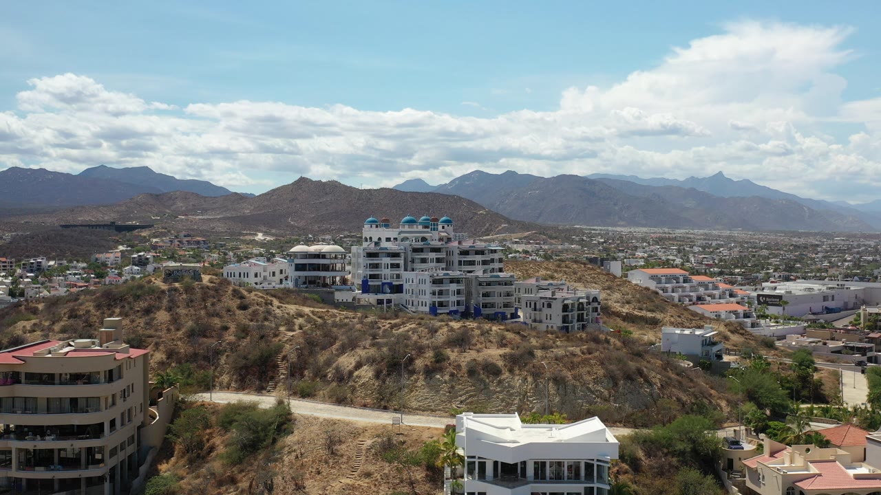 Wide aerial view of hillside condos and distant mountains