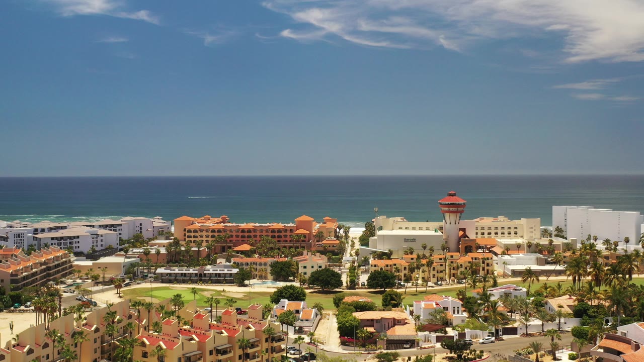 Wide coastal town with ocean horizon and red-topped tower