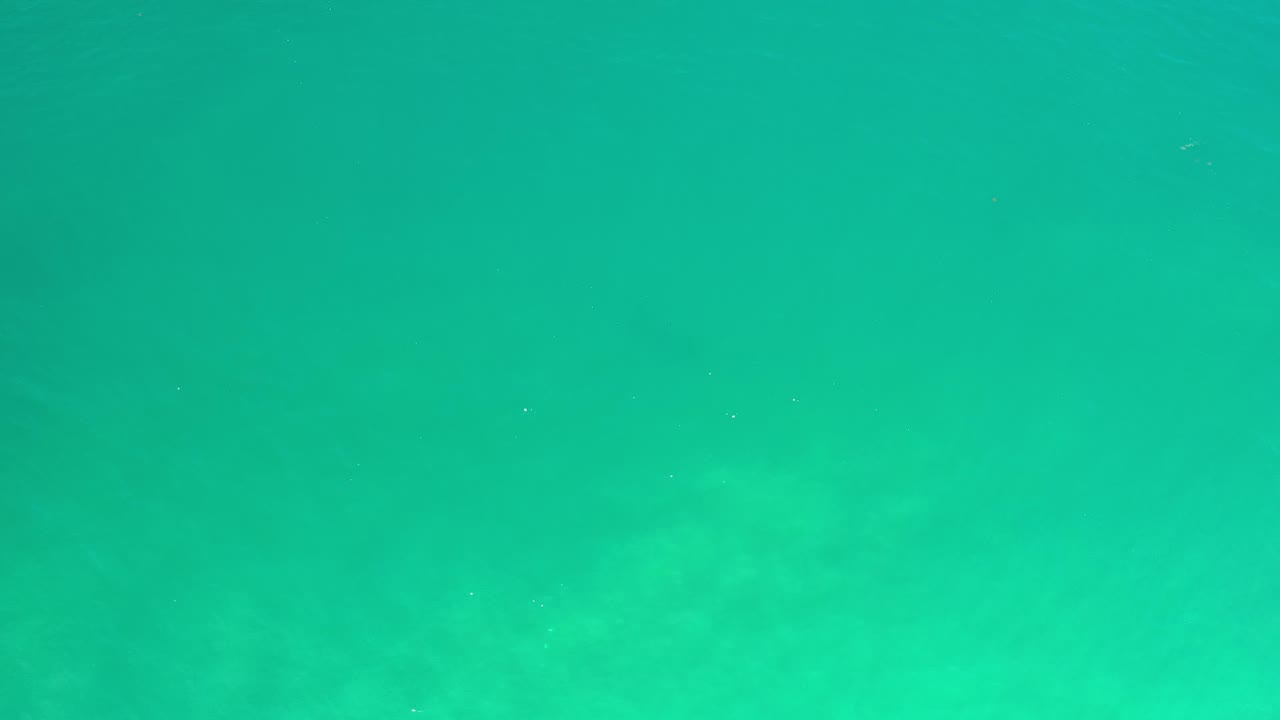 A second underwater frame from Los Cabos, Mexico, showing pale turquoise water, soft uneven light, and no visible people.