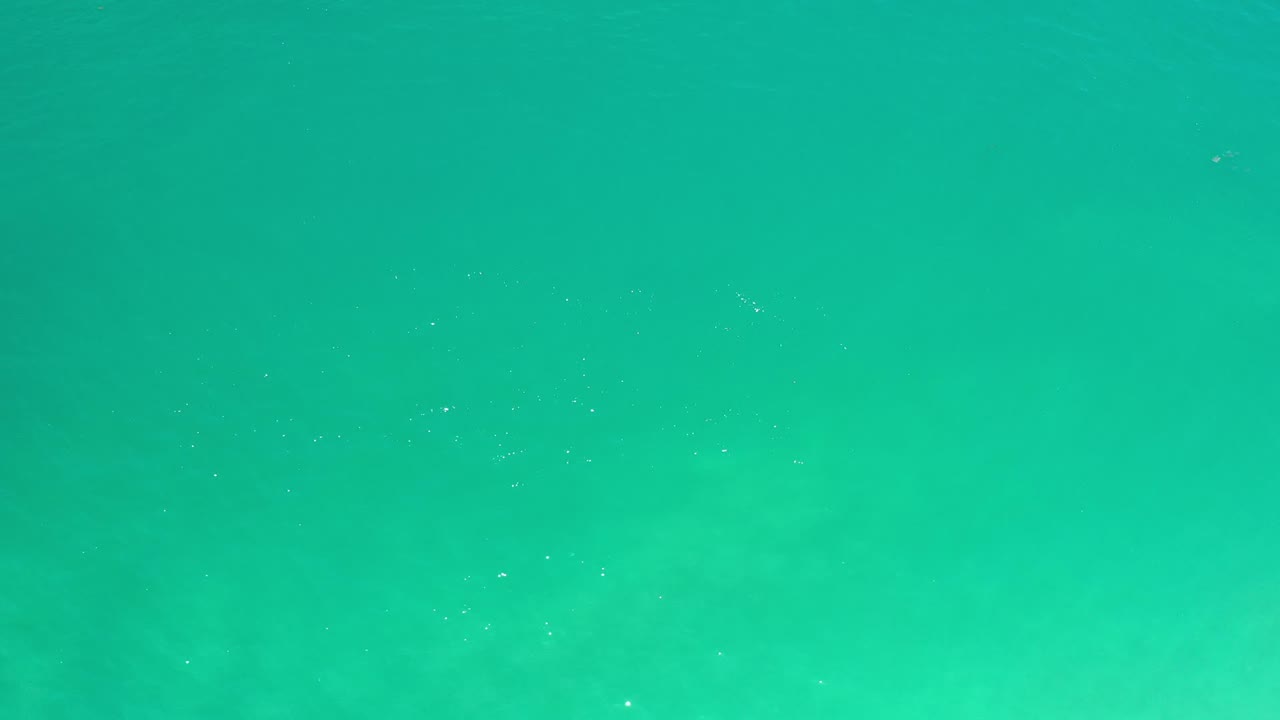Green ocean water fills the second frame in Los Cabos, with a smoother central area, faint white glints, and no visible people.