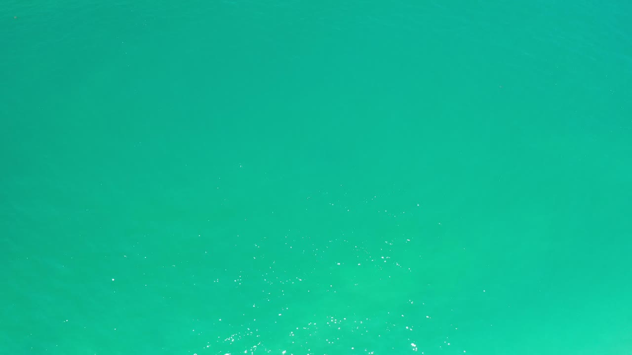 Teal water surface with small white sparkles.
