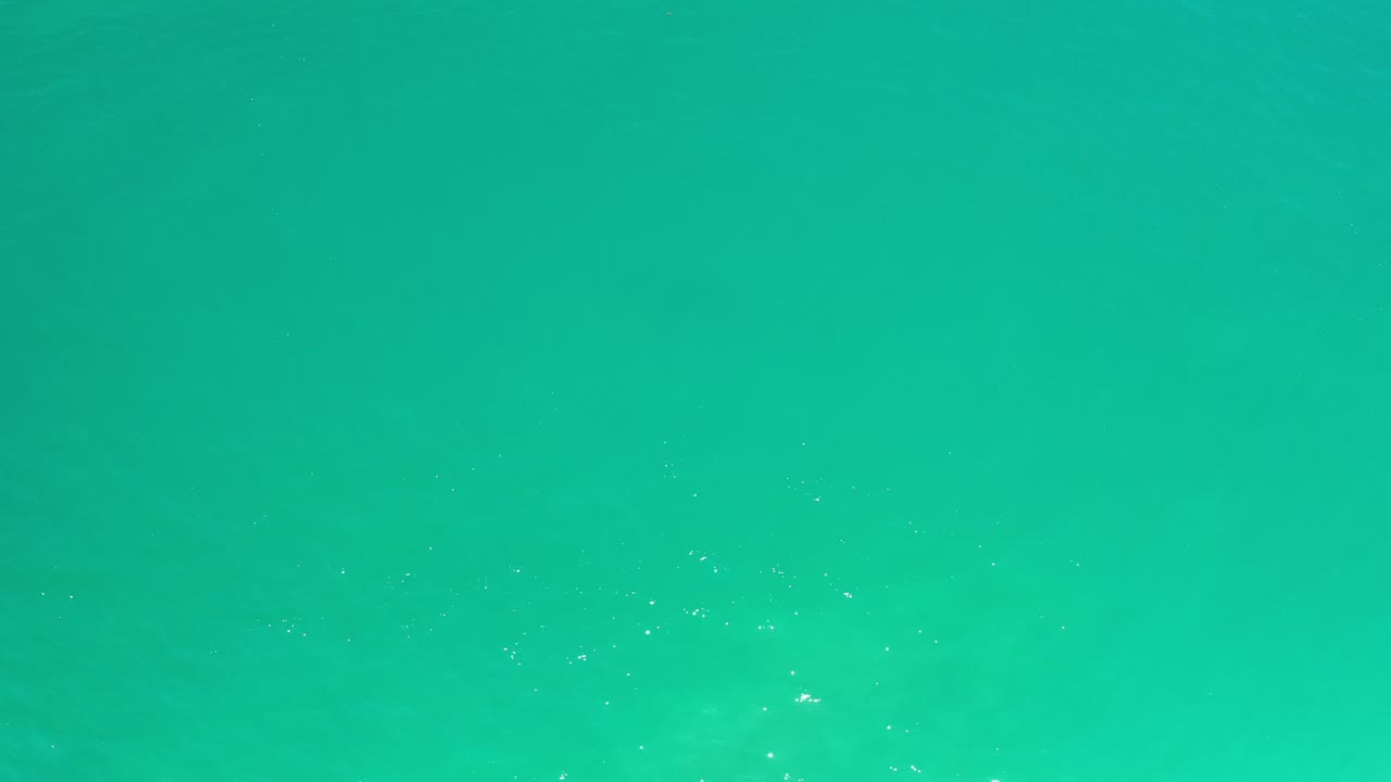 Bright teal sea surface in Los Cabos, Mexico, with scattered sun sparkle and no visible people.