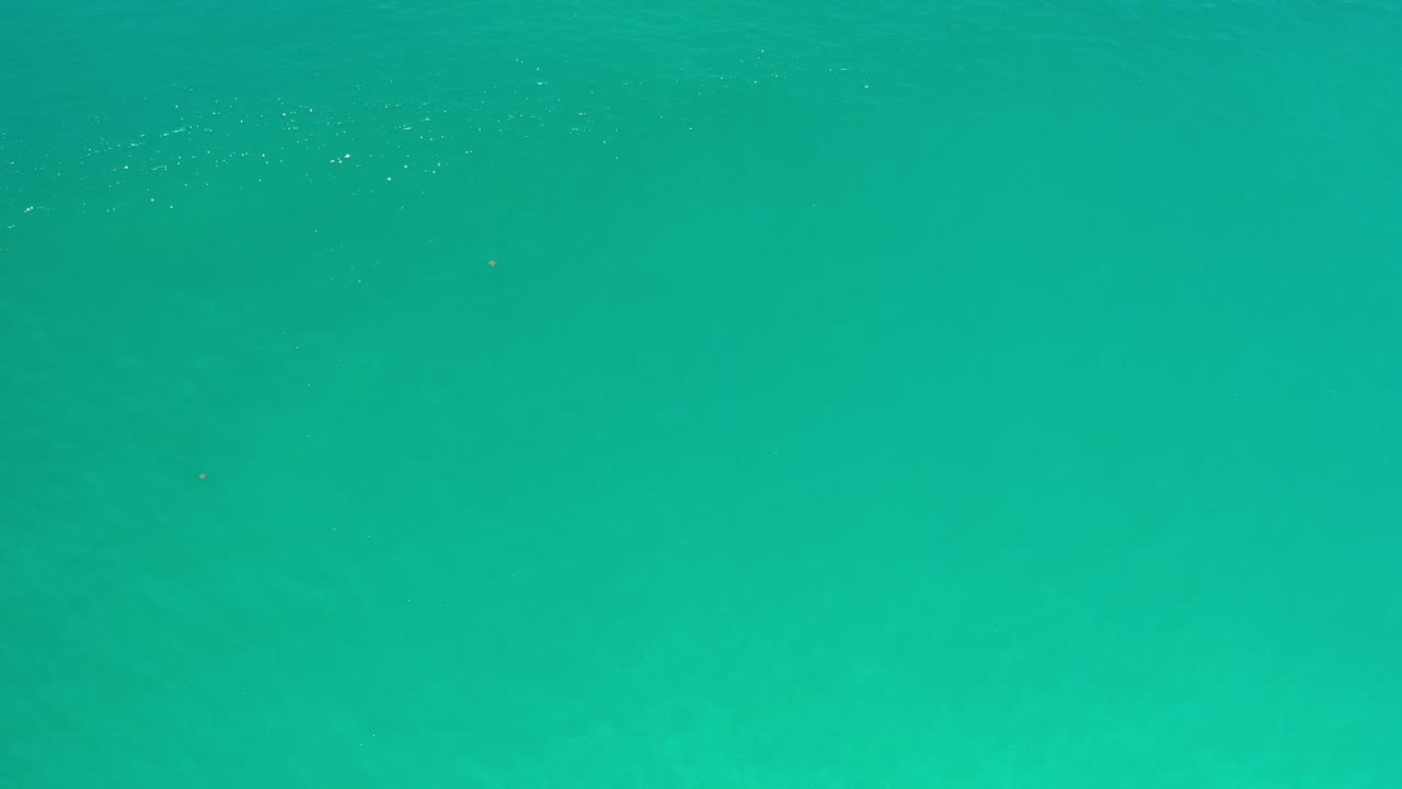 Clear teal seawater fills the frame in Los Cabos, Mexico, with small surface marks and no shoreline or visible people.