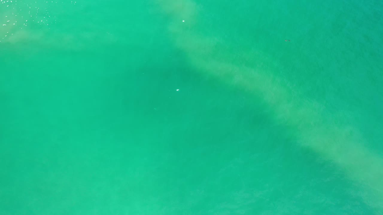 Bright teal ocean water with faint submerged formations.