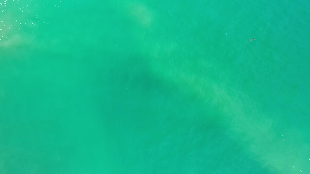 Top-down Los Cabos ocean frame with green-blue water, pale wave wash near the upper area, and no visible people.
