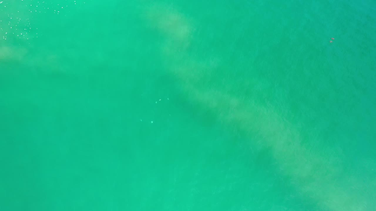 Green ocean water fills the Los Cabos frame, showing faint cloudy movement under the surface and no visible people.