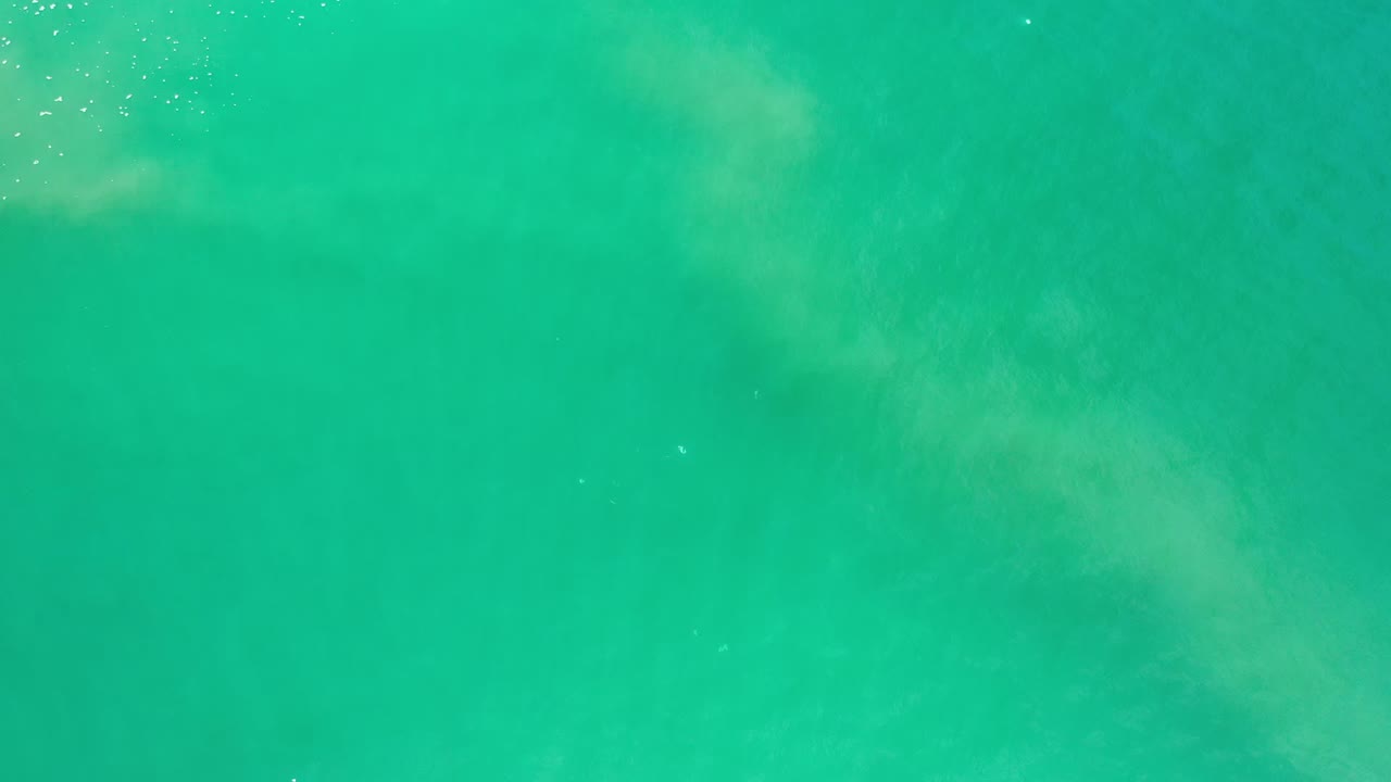 Green-blue ocean water with pale underwater wave patterns.