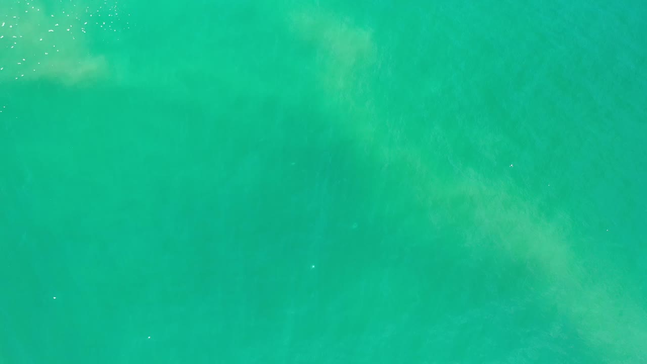 Turquoise water surface with faint cloudy patterns and light ripples.
