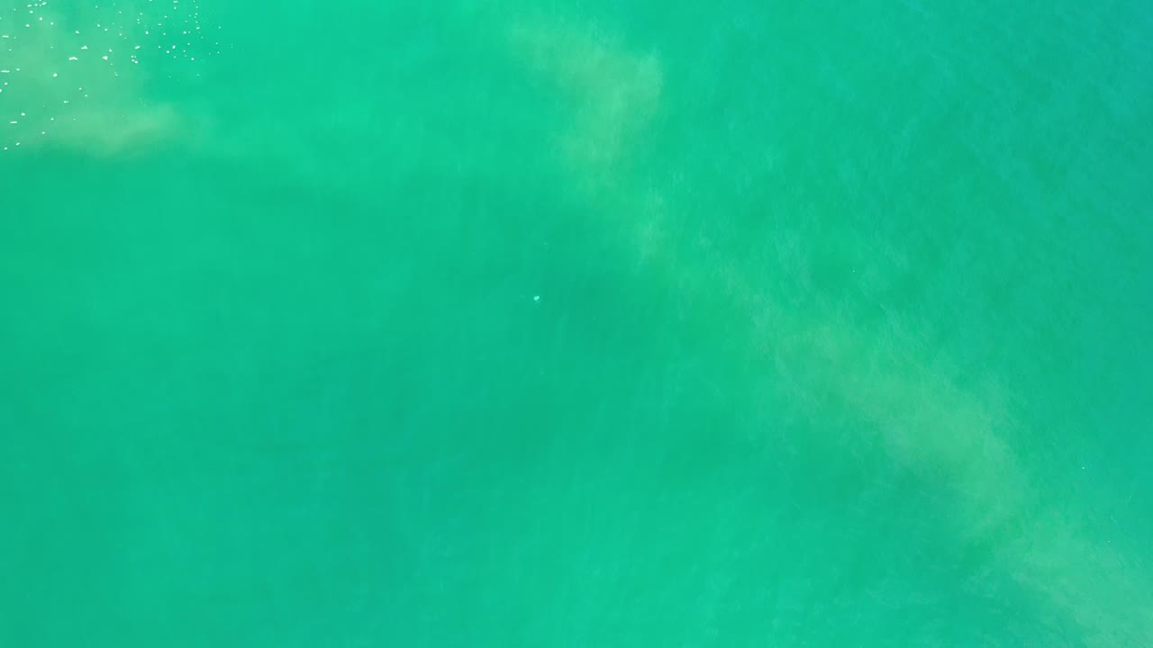 Overhead Los Cabos water frame showing green-blue surface texture, muted pale patches, and no visible people or shoreline.