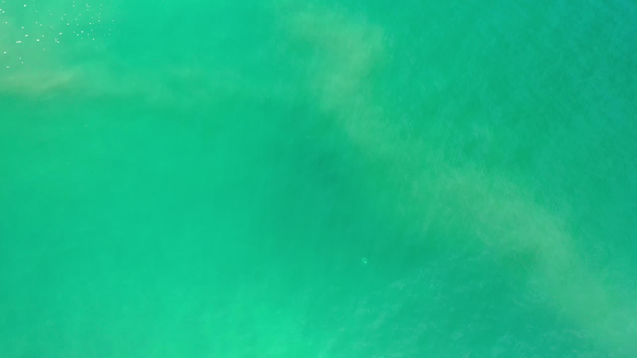 Overhead Los Cabos sea water frame with a denser green field, faint cloudy silt near the upper area, and no visible people.