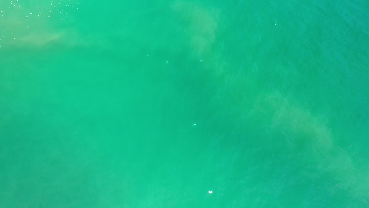 Overhead-looking view of teal ocean water in Los Cabos, Mexico, with soft pale current patterns near the upper left and no visible people.