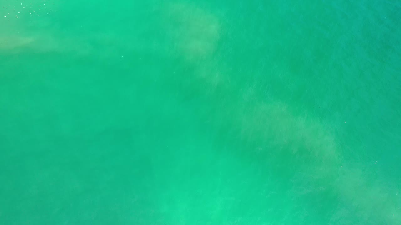 Top-down Los Cabos sea water frame with pale subsurface swirls, scattered sparkle points, and no visible people or shoreline.