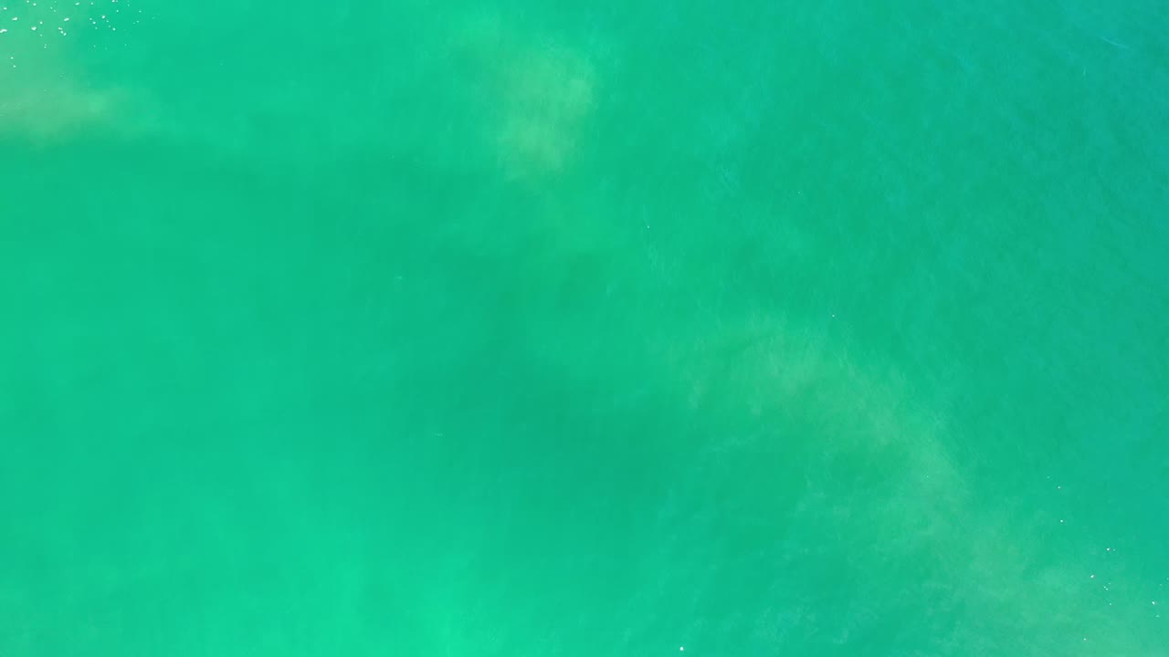 Opening frame of turquoise water in Los Cabos, Mexico, with faint pale patches below the surface, gentle ripples, and no visible people.