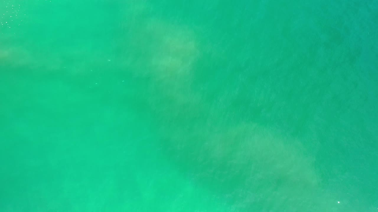Second frame of Los Cabos ocean water, showing a blue-green surface with scattered tiny white specks and no visible people.